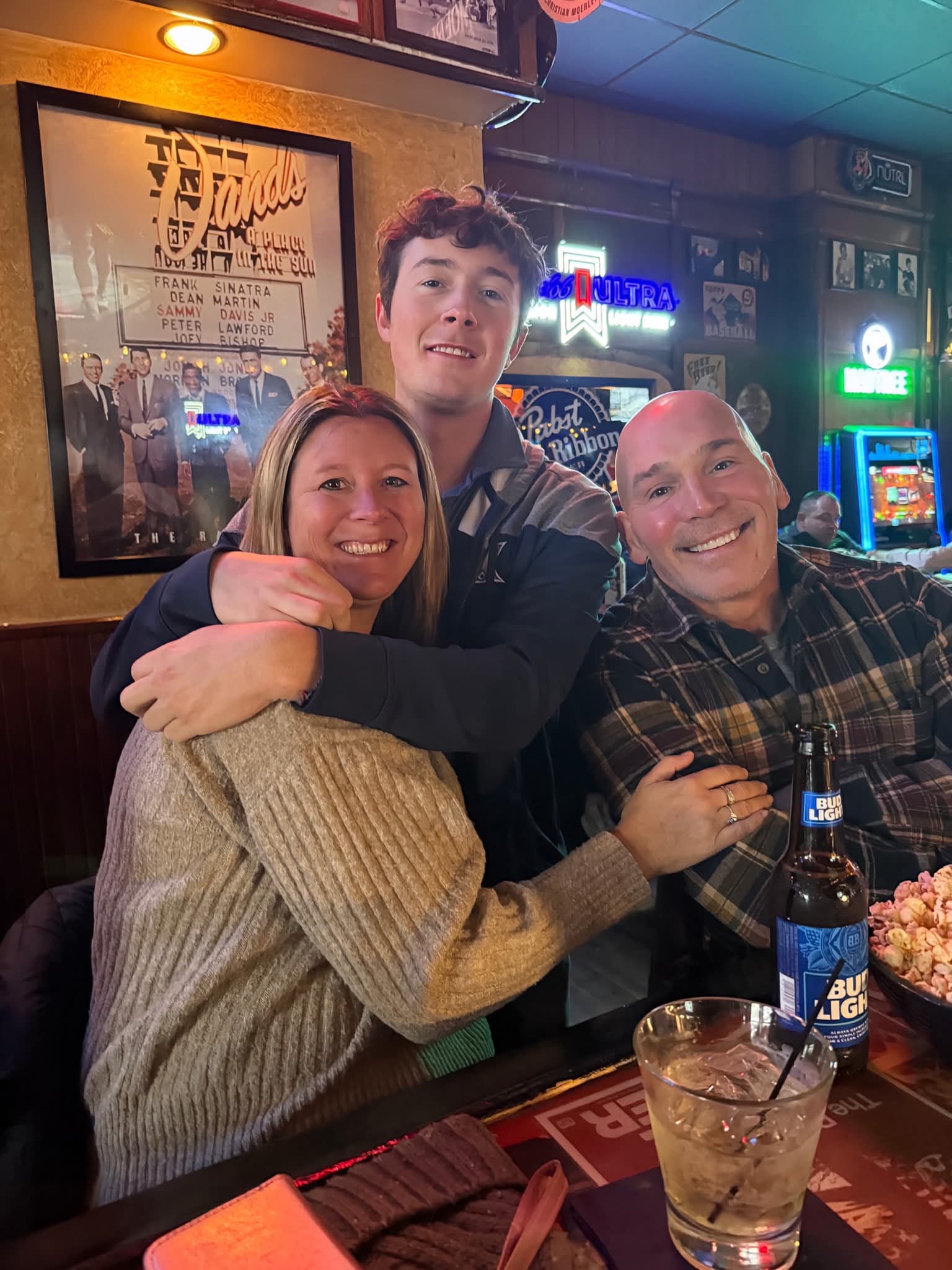 Friends posing under vintage photos at the bar
