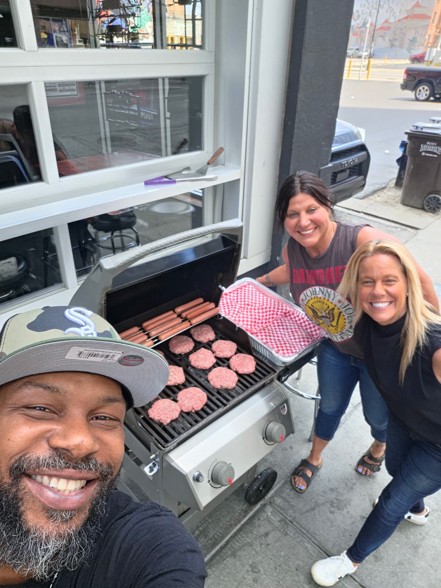 Grilling burgers and hot dogs on the sidewalk outside the bar