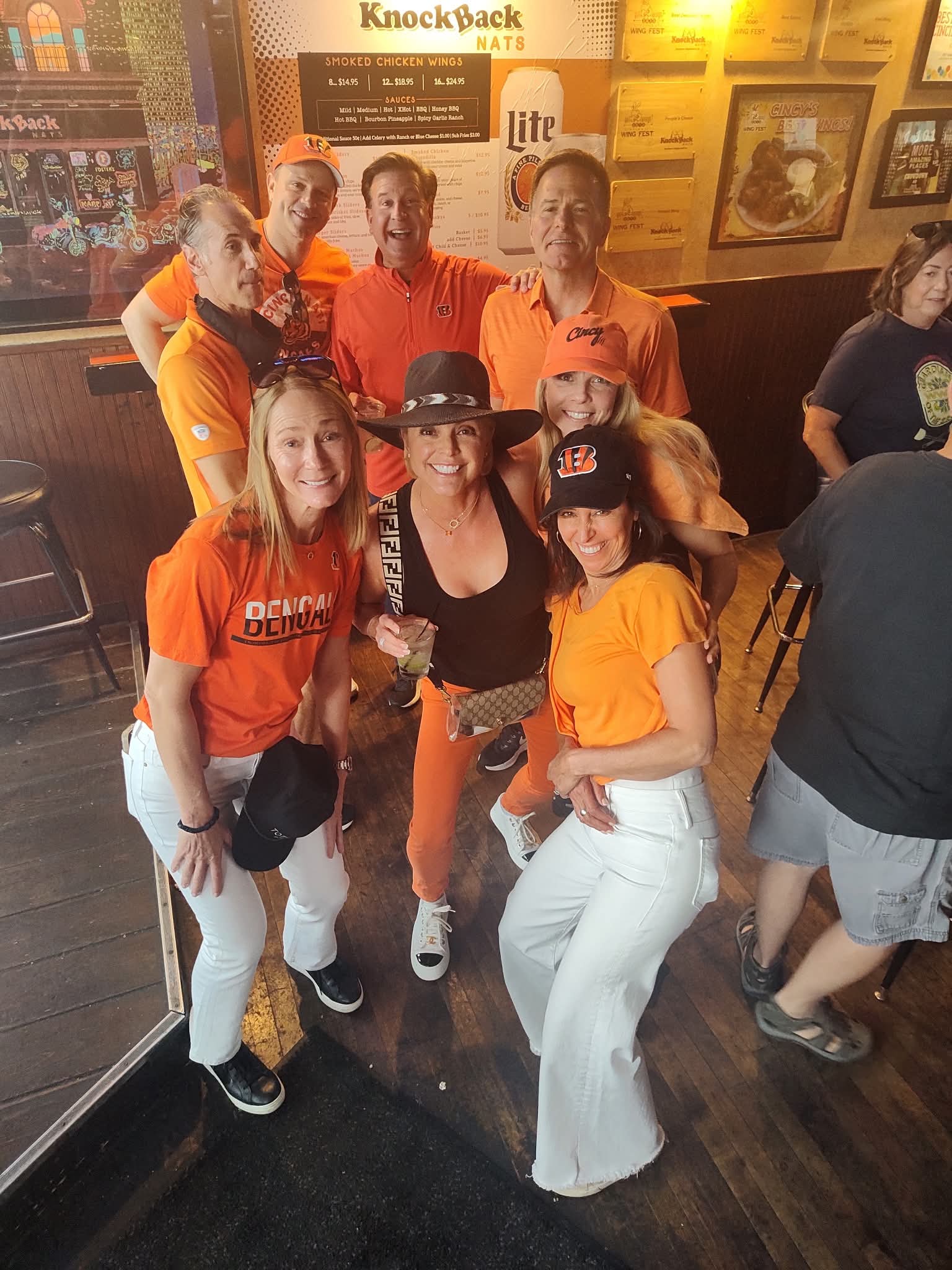 Friends posing in front of the Knockback Nat's wing menu wall