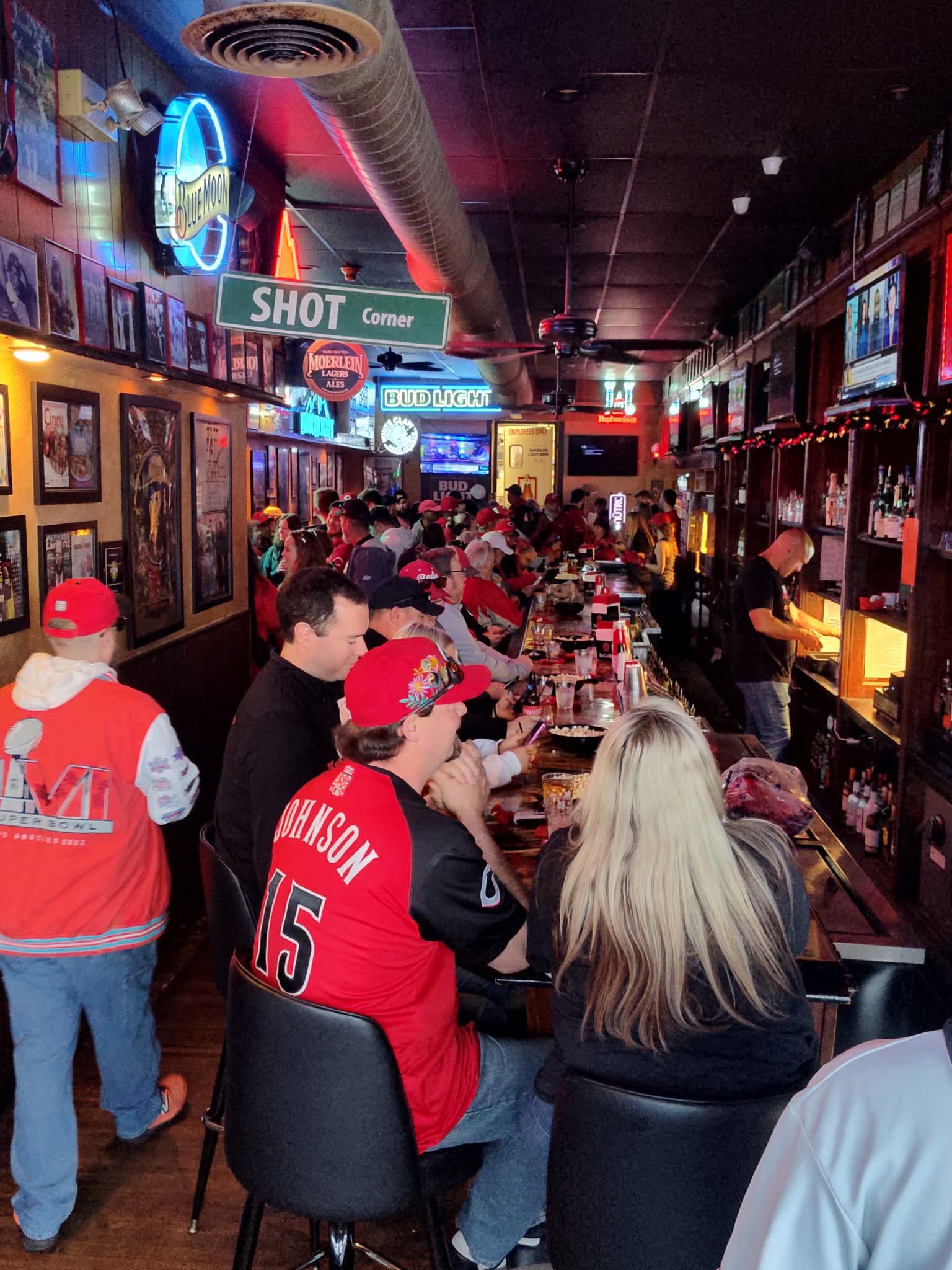 A packed crowd at the bar under the Shot Corner sign