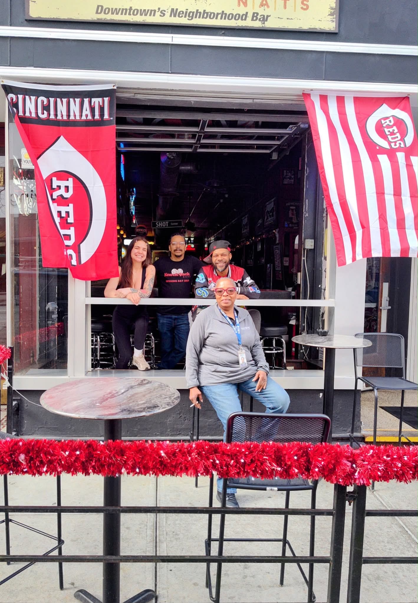 Staff posing in the storefront window with Reds flags