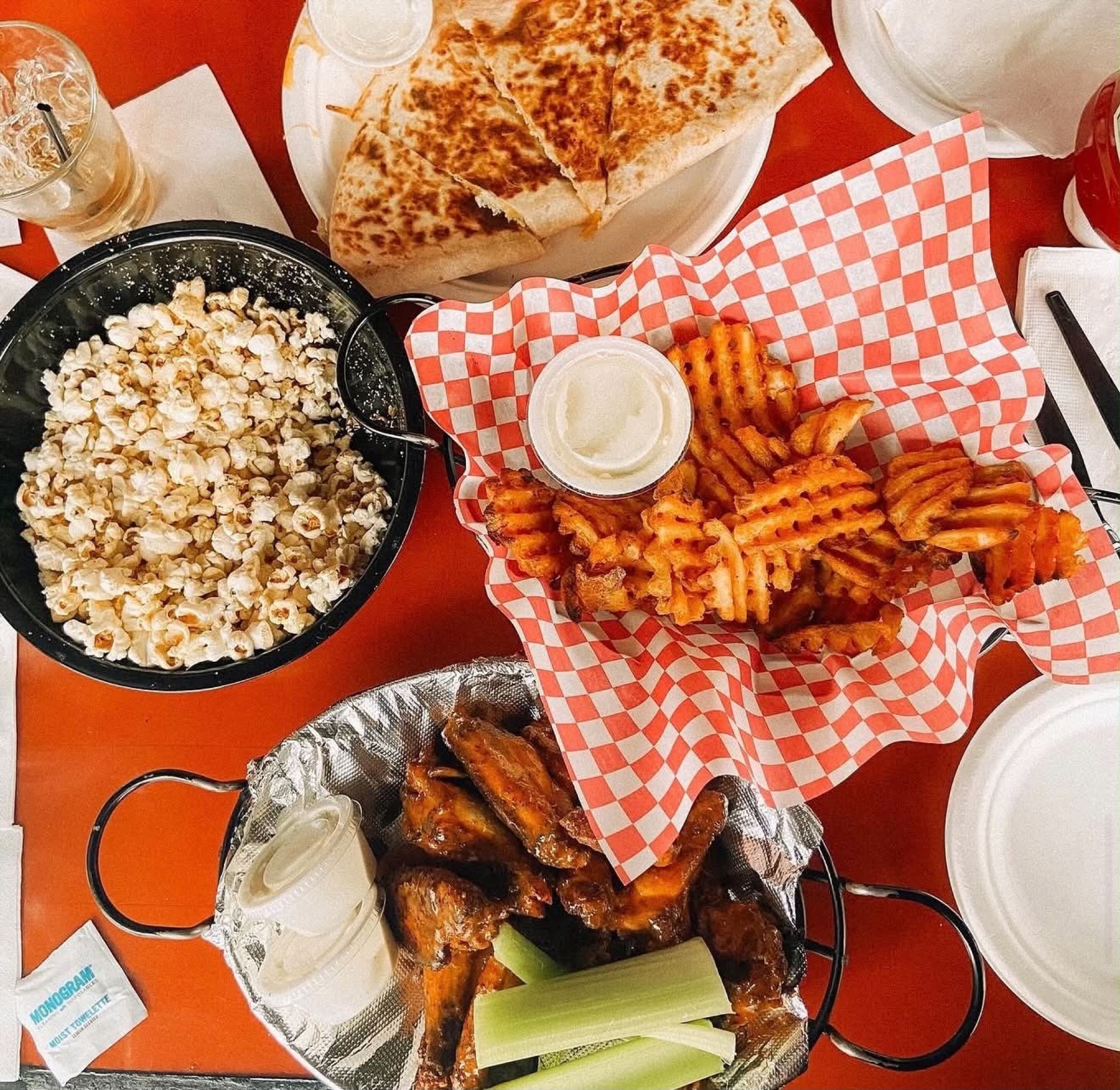 A game-day spread at Knockback Nat's: popcorn, buffalo quesadilla, waffle fries, and smoked wings with celery