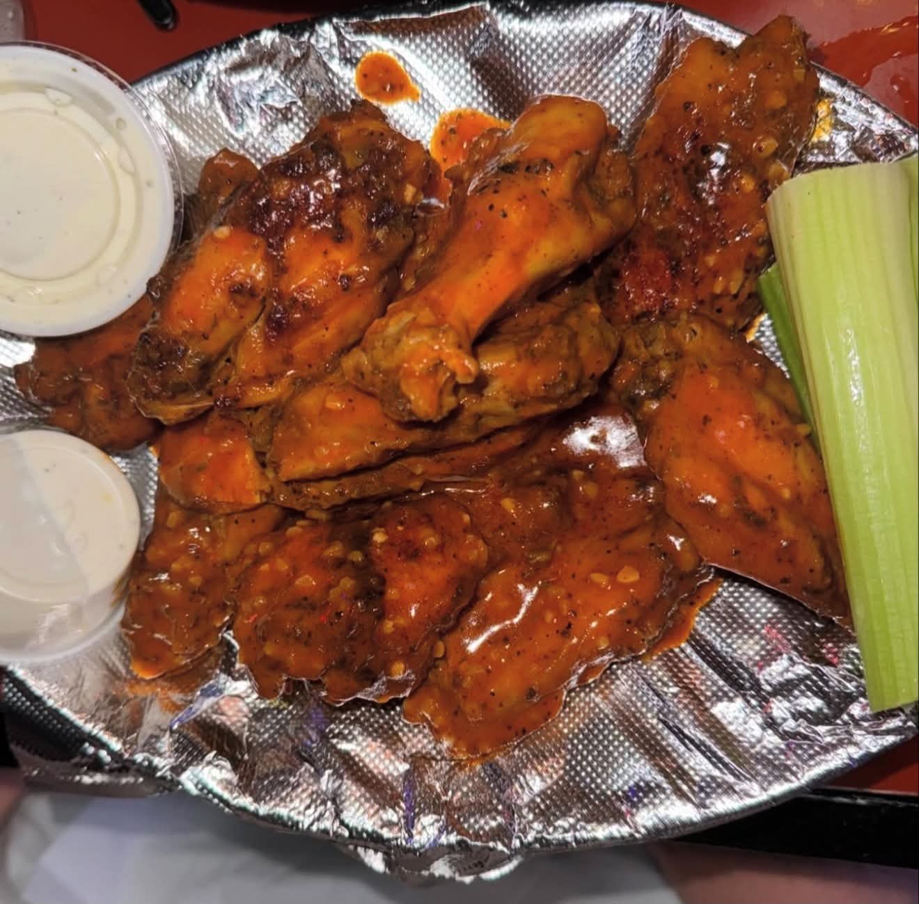 A basket of smoked chicken wings with dipping sauce and celery